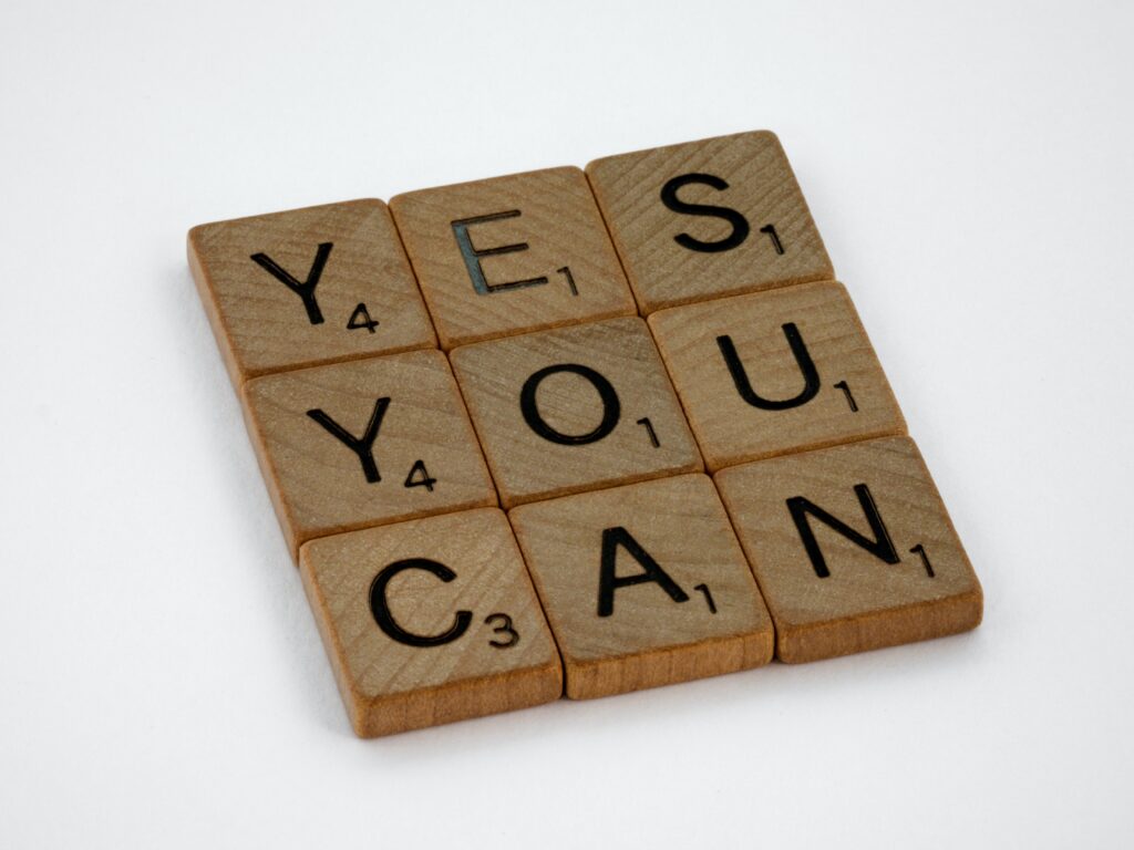Nine wooden scrabble tiles arranged in a pattern, with the letters spelling out "Yes you can"