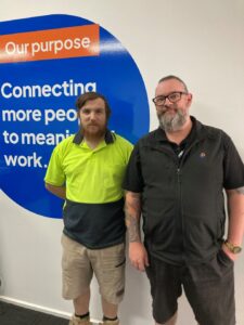 Consultant and participant stand in front of sign in office.