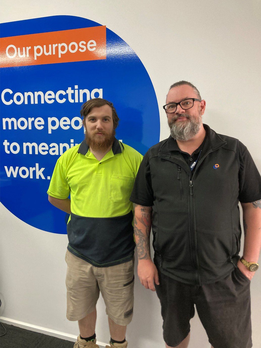 Consultant and participant stand in front of sign in office.